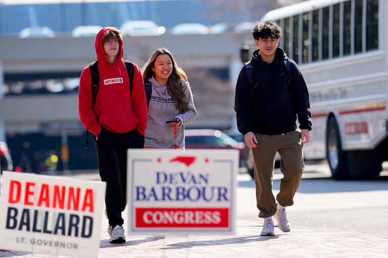 Students walk by election signs on North Carolina State University's campus in Raleigh, N.C.