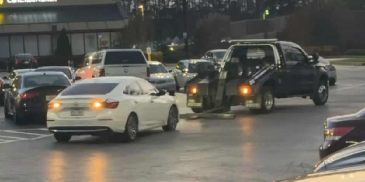 kvinna flyr från en bärgningsbil på en parkeringsplats i ett ovanligt videoklipp