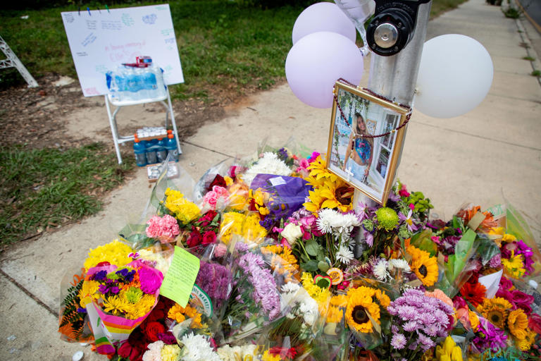 A framed photo of Florida State University sophomore Ellie Sims is placed above dozens of bouquets, candles and cards at the crosswalk sign located at the intersection of Lorene and Pensacola Streets on Wednesday, May 1, 2024. Sims was struck and killed by a driver on Monday.