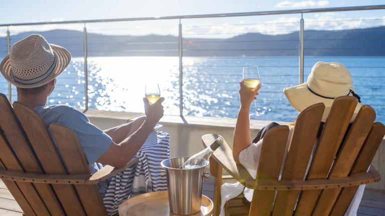 couple holding drinks on cruise balcony