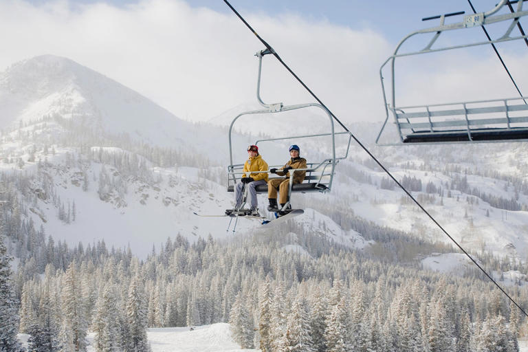 USA, Utah, teenage girl and boy (13-16) sitting on ski lift at Brighton ski resort