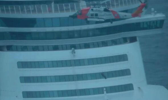 A coast guard helicopter lowering a rescuer onboard the cruise ship