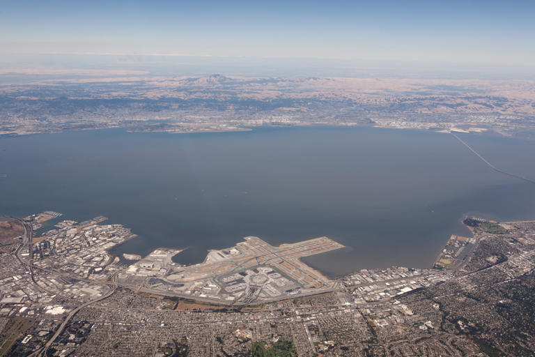 An aerial view of SFO, with OAK visible across the San Francisco Bay.