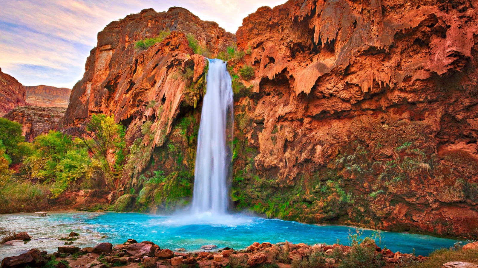 <p>Havasu Falls is a stunning and iconic waterfall located in the Havasupai Indian Reservation, within the Grand Canyon National Park in Arizona, United States. It is known for its crystal-clear turquoise blue waters, cascading over vivid red rock cliffs, creating a breathtaking sight.</p>