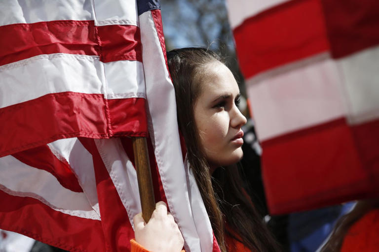Marchers hold American Flags at the March for Our Lives demonstration in New York City on March 24, 2018. New York City. The movement was a result of the Valentine's Day school shooting in Parkland, Florida, that killed 17 students and staff members. Police uncovered a manifesto of a Maryland teen that talked about plans to 'shoot up' schools.
