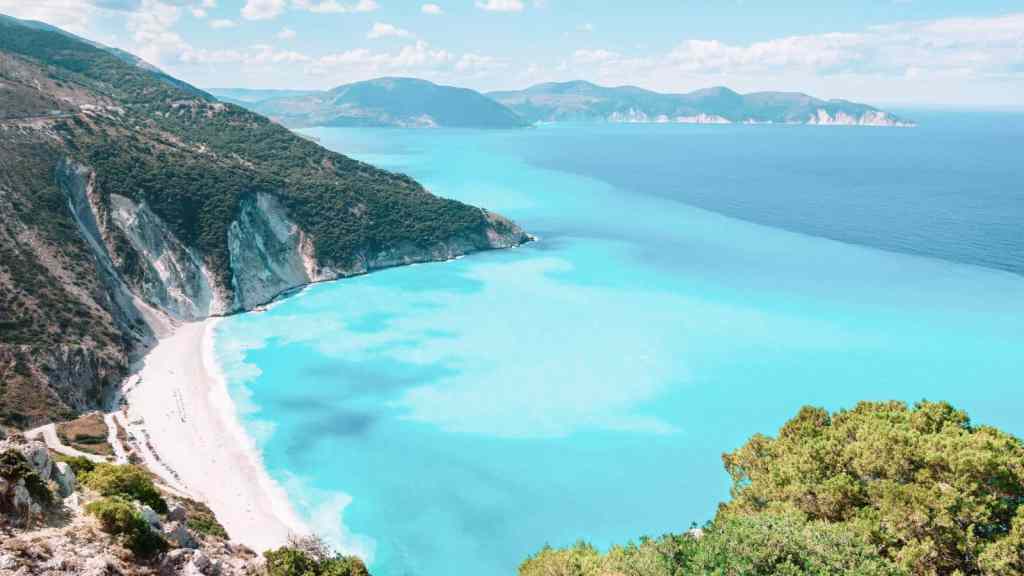 <p>Myrtos Beach on the island of Kefalonia is famous for its vast stretch of white sand and bright blue water. It’s one of the most beautiful beaches on the Greek islands. It is well-organized, with sunbeds and umbrellas available for visitors.</p><p>If you plan to go to Myrtos Beach, try getting there early in the morning. The parking lot can get full quickly because many people want to visit this popular spot. Arriving early will help you find a good parking space and give you more time to enjoy the beach.</p><p>Don’t forget to check out the cool cave at the end of the beach. It’s a fun place to explore, take photos, or just escape from the sun for a little while. Whether you want to swim, sunbathe, or relax, Myrtos Beach is a great place to spend the day.</p><p class="has-text-align-center has-medium-font-size">Read also: <a href="https://worldwildschooling.com/landmarks-in-greece/">Amazing Landmarks in Greece</a></p>