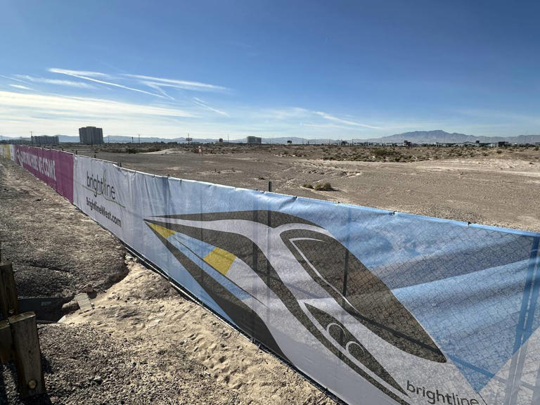 A fence with Brightline West imagery sits on a plot of land where the Las Vegas station of the high-speed rail system would be built on Monday, Dec. 4, 2023.
