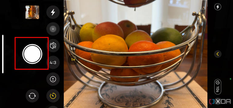 A bowl of fruit on a table framed by the iPhone camera with the shutter button selected.