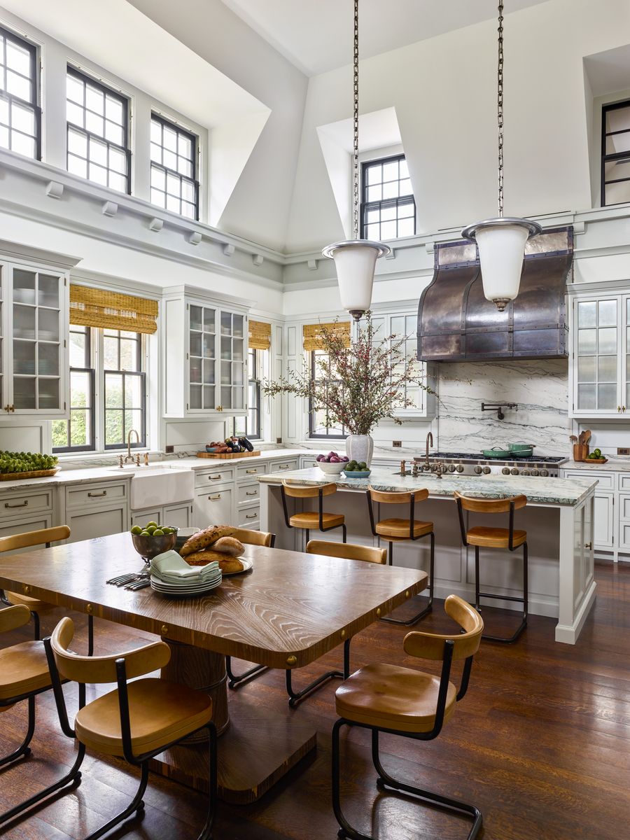 <p>In <a href="https://www.veranda.com/decorating-ideas/house-tours/a42046010/steven-gambrel-new-jersey-house-tour/">this 1920s New Jersey estate designed by Steven Gambrel</a>, the profiles of the cabinetry and moldings echo those of adjoining rooms, as do the kitchen's dark wood floors. “Not long ago you’d walk into a kitchen and it wouldn’t speak to the rest of the house,” says Gambrel. “I like to make kitchens equally complex and layered.” He added dramatic details such as a gunmetal-and-brass hood, a veneered table, and textured shades to the space. The golden leather cantilever seating (<a href="http://www.yorkstreet.com/">York Street Studio</a>) juxtaposes tonal gray millwork. The island countertop is crafted of indigo green marble. Range, <a href="https://www.bluestarcooking.com/cooking/ranges/">BlueStar</a> </p>