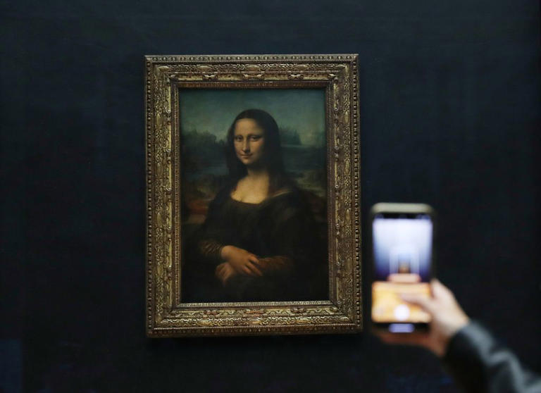 A visitor takes a photo of the painting Mona Lisa at the Louvre Museum in Paris, France, on May 19, 2021.