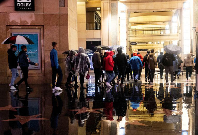 FILE PHOTO: A group of tourists walk on Hollywood Boulevard during an ongoing rain storm in Los Angeles, California, U.S., February 5, 2024. REUTERS/Aude Guerrucci/File Photo