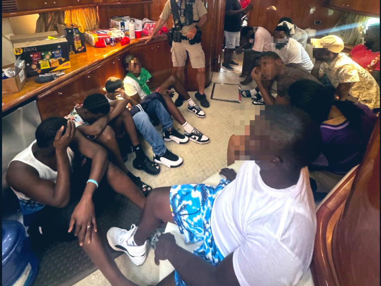 A group of people from Haiti sit below the deck of a 60- foot yacht that was stopped by local police and federal agents near Key Biscayne, Florida, on Friday, April 19, 2024.