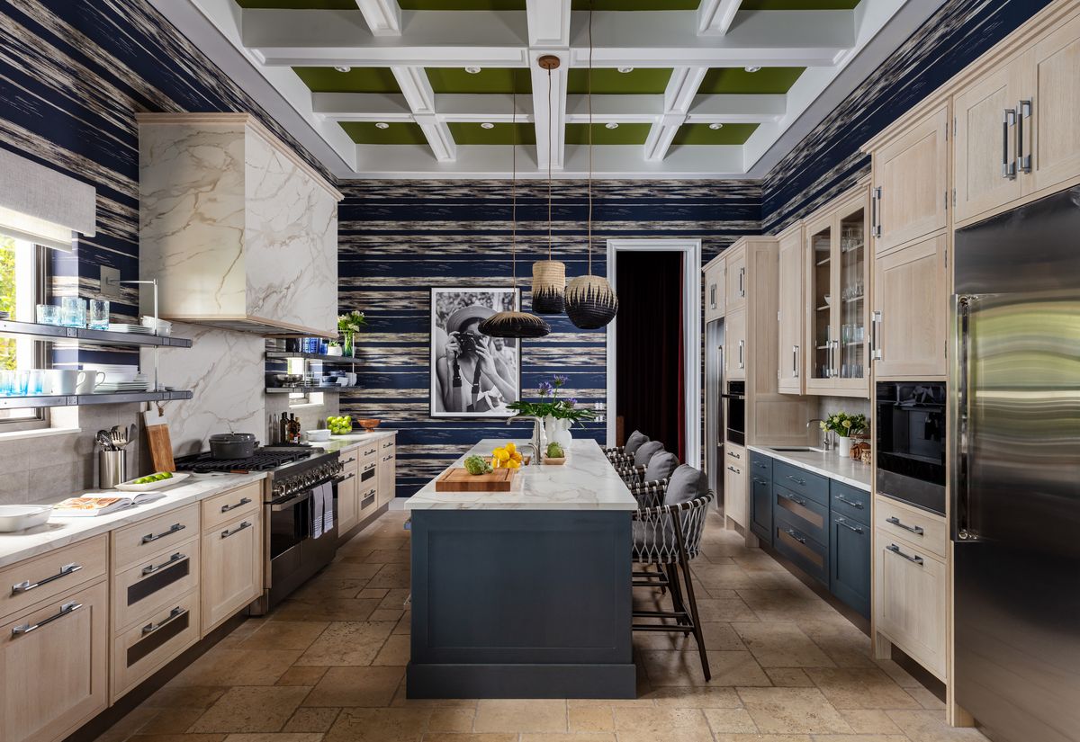 <p>Sleek bleached wood cabinetry and slab-front drawers from <a href="https://peacockhome.com/collections/kitchen-collections/montauk">Christopher Peacock’s Montauk collection</a> are paired with an island and wet bar cabinetry stained slate blue for contrast. Earthy Dekton Onirika in Morpheus Velvet design from <a href="https://www.cosentino.com/">Cosentino</a> repeats on counters, backsplash, and vent hood with a shagreen leather-inspired limestone tile cloaking the walls of the kitchen in <a href="https://www.veranda.com/decorating-ideas/a43012650/tour-2023-kips-bay-decorator-show-house-palm-beach/">the 2023 Kips Bay Decorator Show House Palm Beach</a>.</p>