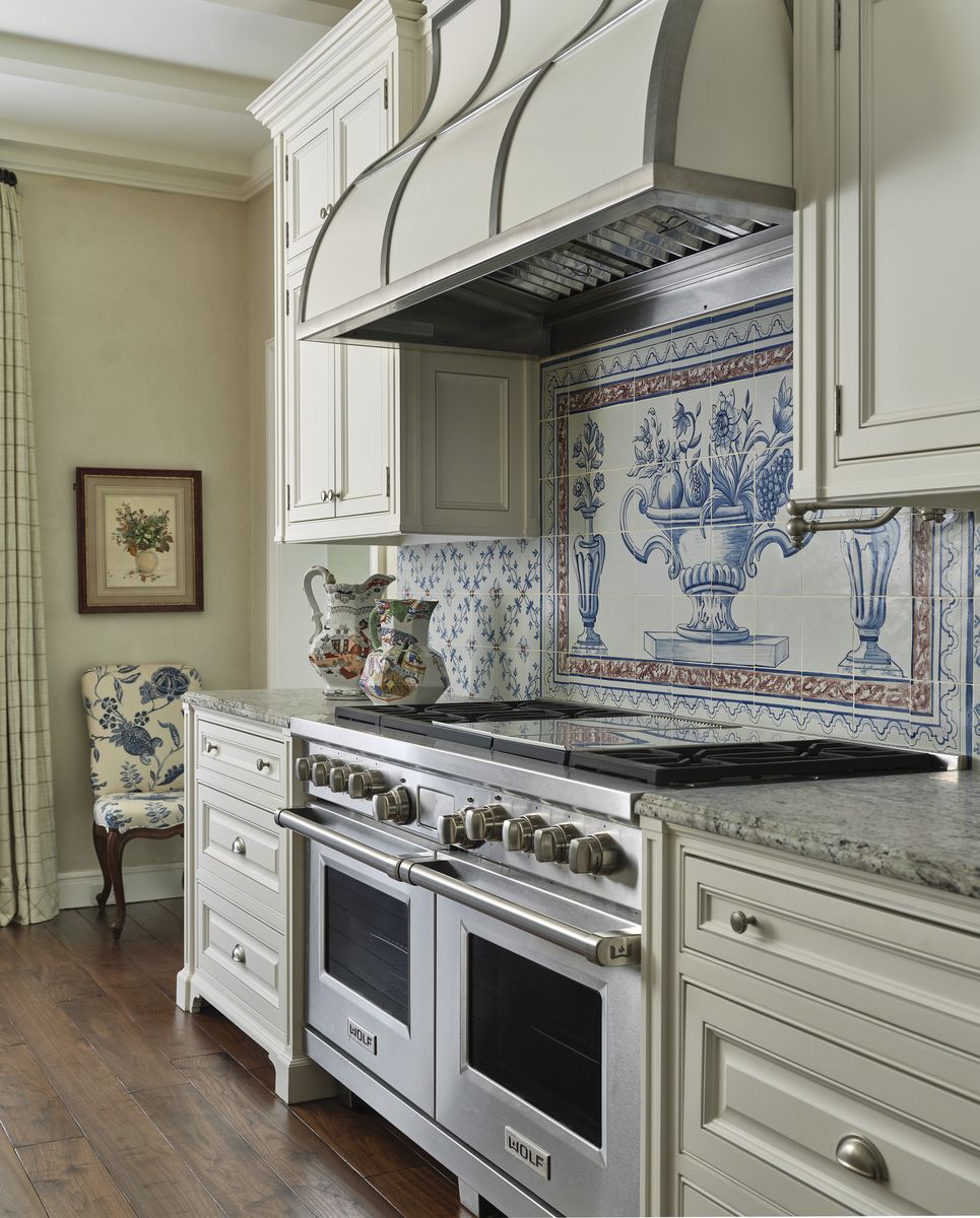 <p>Portuguese tiles form a kitchen backsplash mural akin to classical artwork in <a href="https://www.veranda.com/decorating-ideas/house-tours/a43474734/charlotte-moss-houston-home-tour/">this 1920s Tudor in Houston designed by Charlotte Moss</a>. Upper and lower cabinets in a calming neutral leave room for the show-stopping tilework. </p>
