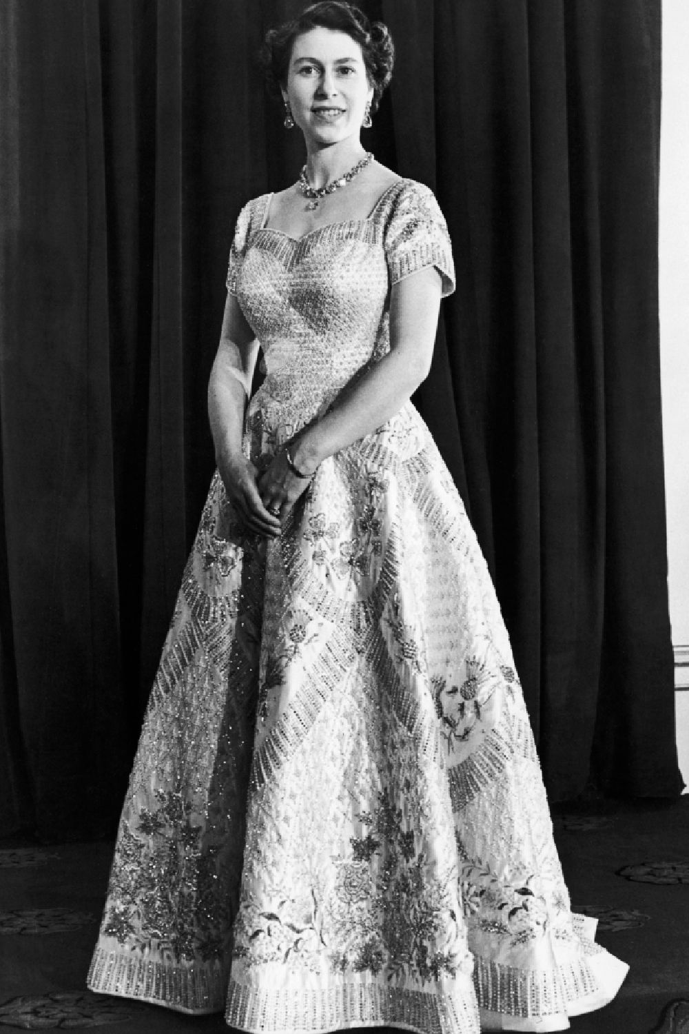 <p>                     Her Majesty's stunning coronation dress was crafted from white stain and embroidered in gold and silver thread with some significant images for those if you were to look closely enough. The dress, designed by British fashion designer Norman Hartnell, was adorned with emblems of the United Kingdom and the Commonwealth.                   </p>