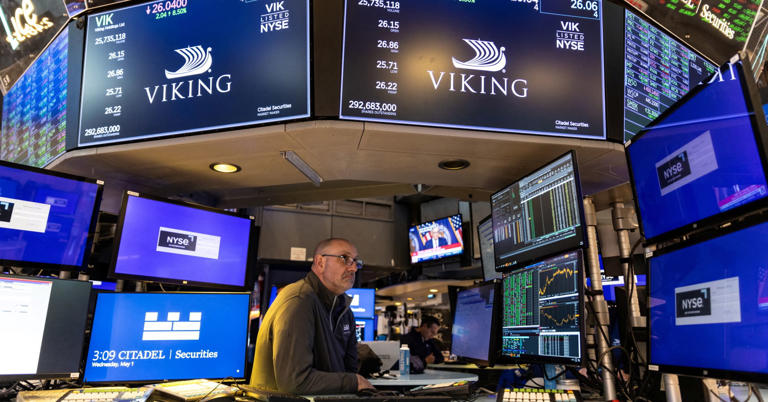 A trader works inside a booth, as screens display Viking cruise company logo, on the floor of the New York Stock Exchange. 