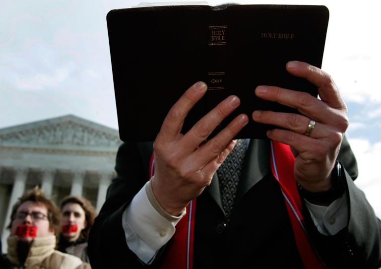 On January 31, 2006, a pastor holds a Bible while praying in front of the U.S. Supreme Court in Washington, D.C. Conservatives criticized Republicans for supporting a bill they believe could make the Bible “illegal.”