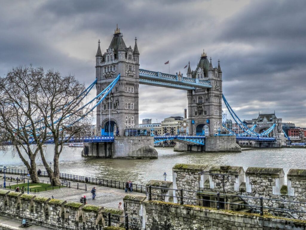 <p>Tower Bridge in London is a combined bascule and suspension bridge, known for its Victorian Gothic style and distinctive twin towers. Its design allows it to open to accommodate river traffic while maintaining its structural integrity.</p>