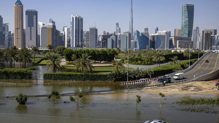 An abandoned vehicle in flood waters caused by heavy rains, with the Burj Khalifa