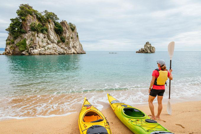 A Woman Is Sea Kayaking The Coastline Of Abel Tasman National Park South Island New Zealand