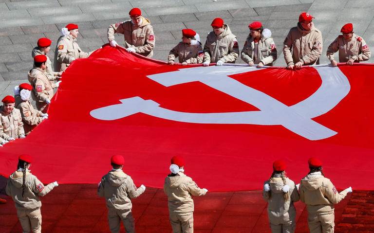 Russians hold a giant replica of the victory banner as they attend an event commemorating victory in WWII near the Museum of the Great Patriotic War in Moscow - EPA-EFE/YURI KOCHETKOV