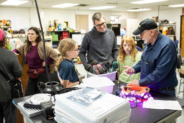 Volunteer fixer Chuck Reavis, right, who ran a transmission shop for over 10 years and taught automotive technology, talks to the Pyles family, of Saline, as they brought in remote vehicles and holiday lights to repair during Fix-It Friday at Maker Works in Ann Arbor on Friday, April 19, 2024.
