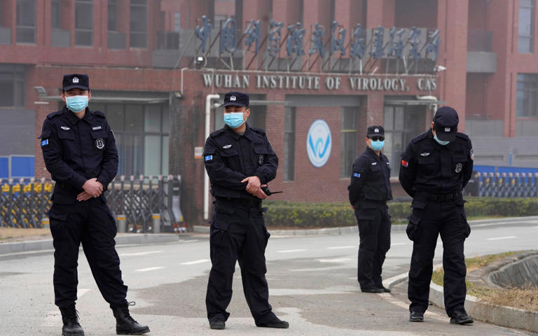 Security personnel gather near the entrance of the Wuhan Institute of Virology during a visit by the World Health Organization team - NG HAN GUAN/AP