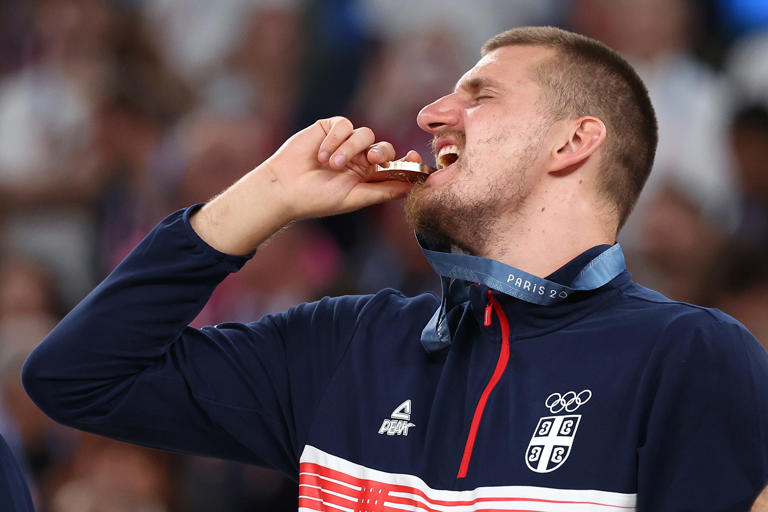 PARIS, FRANCE - AUGUST 10: Bronze medalist Nikola Jokic of Team Serbia bites his medal while posing for a photo on the podium during the Men's basketball medal ceremony on day fifteen of the Olympic Games Paris 2024 at Bercy Arena on August 10, 2024 in Paris, France. (Photo by Ezra Shaw/Getty Images) ORG XMIT: 776138674 ORIG FILE ID: 2166240027