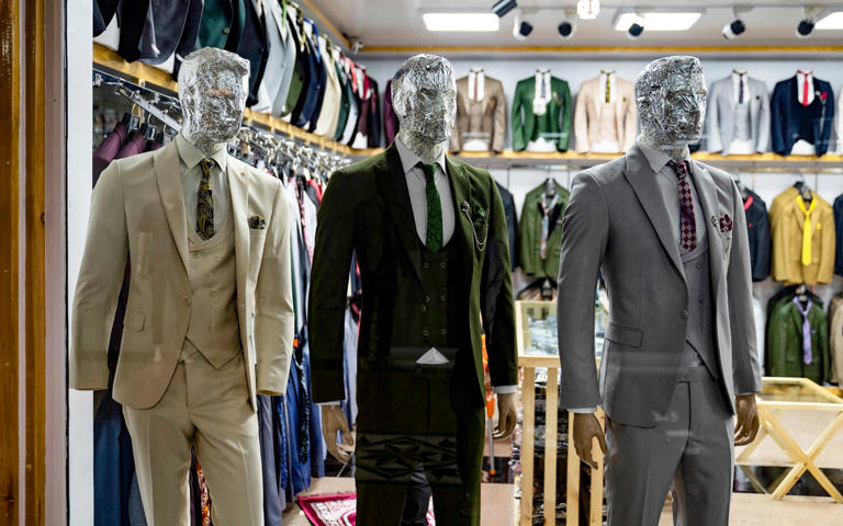 Male mannequins wearing three-piece wedding suits have their faces covered in tin foil - WAKIL KOHSAR/AFP