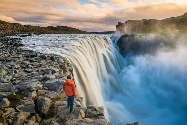 Tourist admiring Dettifoss waterfall at sunset