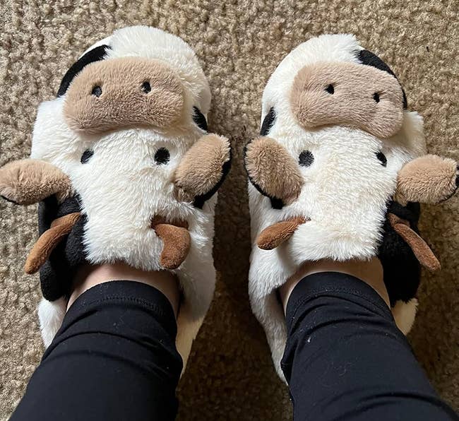 reviewer wearing plush cow slippers