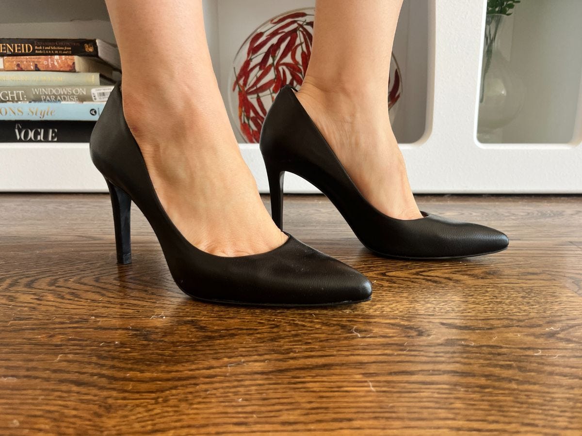 close up picture of black high heeled pumps on a wood floor