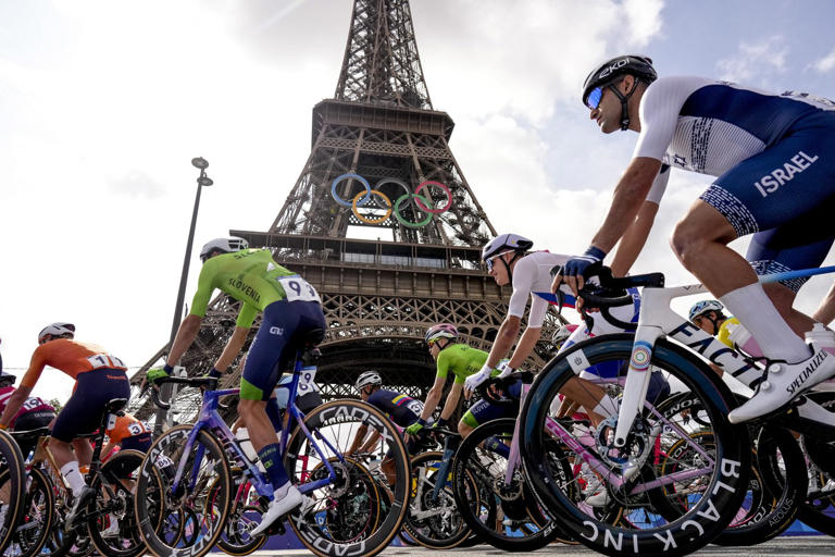 Competitors pass by the Eiffel Tower as they start the men's road cycling event, at the 2024 Summer Olympics, Saturday, Aug. 3, 2024, in Paris, France. (AP Photo/Thibault Camus)