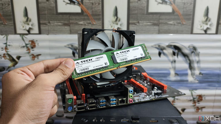 A person holding a DDR4 ECC memory module in front of an X99 dual-Xeon motherboard