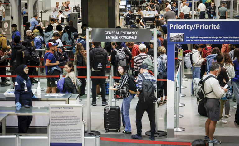 Passengers line up to pass through security as repairs are underway at the Calgary International Airport after parts of its domestic terminal building were closed late Monday due to damage caused by hail and heavy rainfall in Calgary on Tuesday, Aug. 6, 2024. WestJet says 16 of its planes have been grounded after the massive hailstorm hit Calgary. THE CANADIAN PRESS/Jeff McIntosh