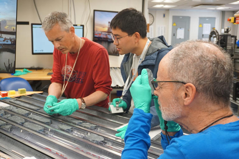 Professor Johan Lissenberg (left) and colleagues analyzing the cores, which were recovered from a “tectonic window” on the Mid-Atlantic Ridge. CREDIT: Lesley Anderson, Exp. 399, JRSO_IODP