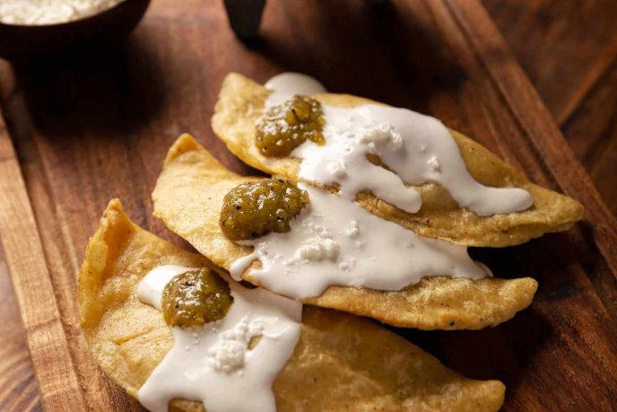 Quesadillas fritas de chicharron sobre tabla de madera 