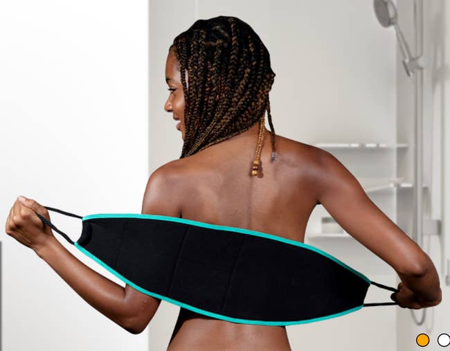 A model using a black handle-strapped exfoliating back scrubber