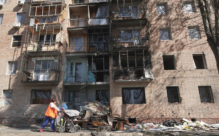 A woman walks past a building damaged by Ukrainian strikes in Kursk on August 16, 2024, following Ukraine's offensive into Russia's western Kursk region.