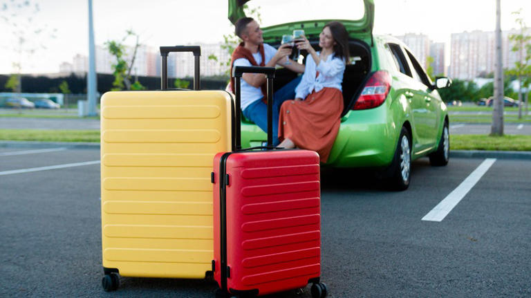 Traveling couple toasting, seated in car trunk