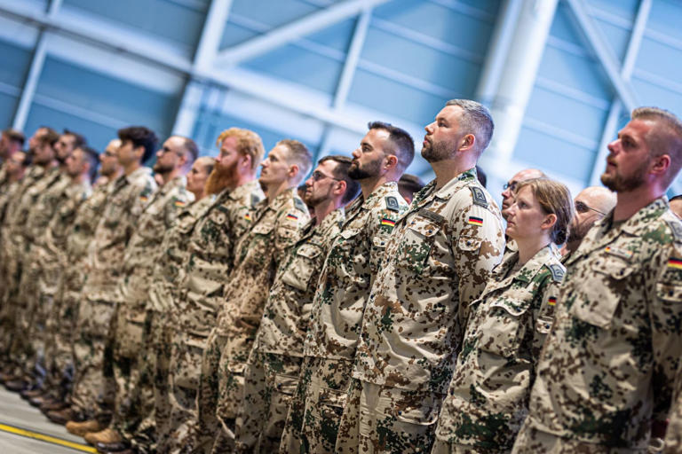 Bundeswehr soldiers stand in a hangar at Wunstorf Air Base in the Hanover region in the evening for a return roll call. The German armed forces have ended an eight-year deployment to Niger after surrendering control of a key airbase in the West African country. Moritz Frankenberg/dpa