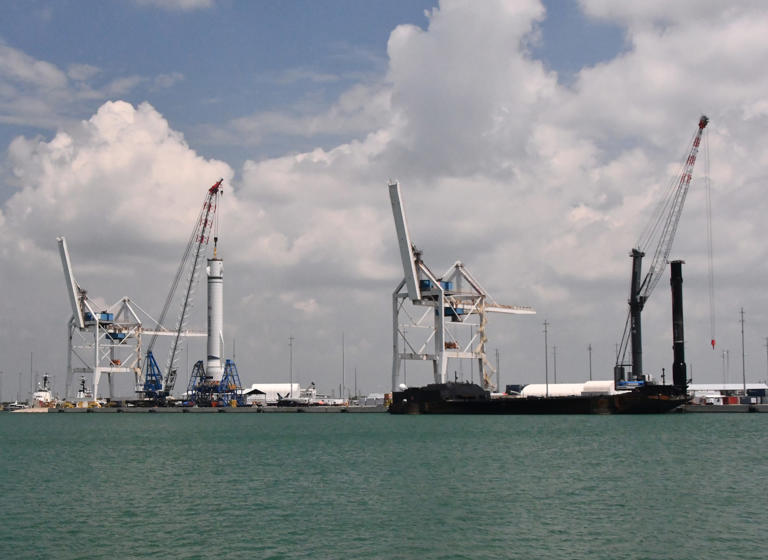 The cargo cranes at Port Canaveral simultaneously handled a Blue Origin New Glenn mockup booster, at left, and a SpaceX Falcon 9 booster, on the right.