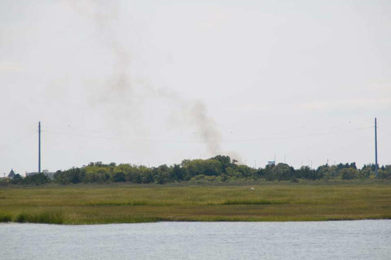 Plumes of smoke from a boat fire at a Wildwood, New Jersey, marina appear above the marshlands on Thursday, Aug. 22, 2024.