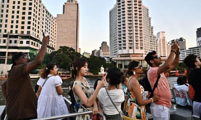 Tourists look at the view from the top deck of a tourist commuter boat on the Chao Praya River in Bangkok on Dec. 27, 2023. Photo by AFP