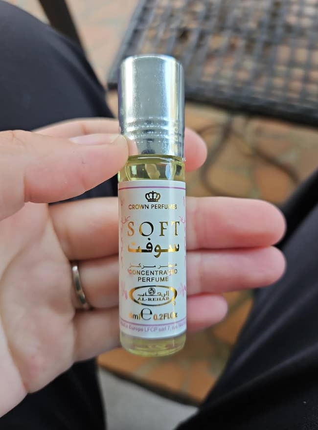 A hand holding a small bottle of Crown Perfumes'