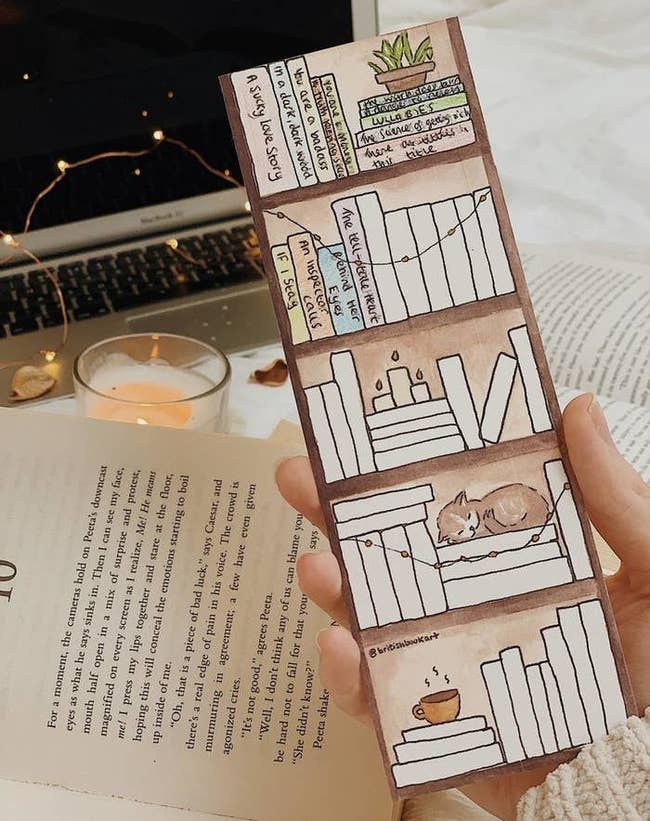 a person holding the bookmark with blank books on painted shelves