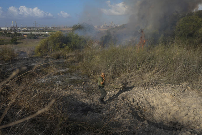 A police officer inspects the area around a fire after the military said it fired interceptors at a missile launched from Yemen that landed in central Israel on Sunday, Sept. 15, 2024. (AP Photo/Ohad Zwigenberg)