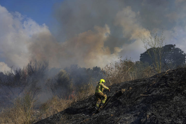 A firefighter works in the area around a fire after the military said it fired interceptors at a missile launched from Yemen that landed in central Israel on Sunday, Sept. 15, 2024. (AP Photo/Ohad Zwigenberg)