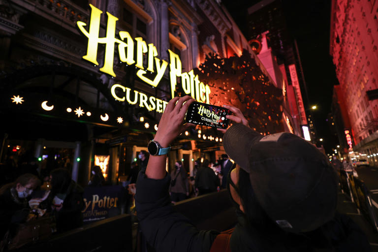 A passerby takes a photo of the " Harry Potter and the Cursed Child" marquee at the Lyric Theatre before the evening show on Dec. 16, 2021, in New York.