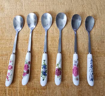 Six silver spoons with floral-patterned handles arranged in a row